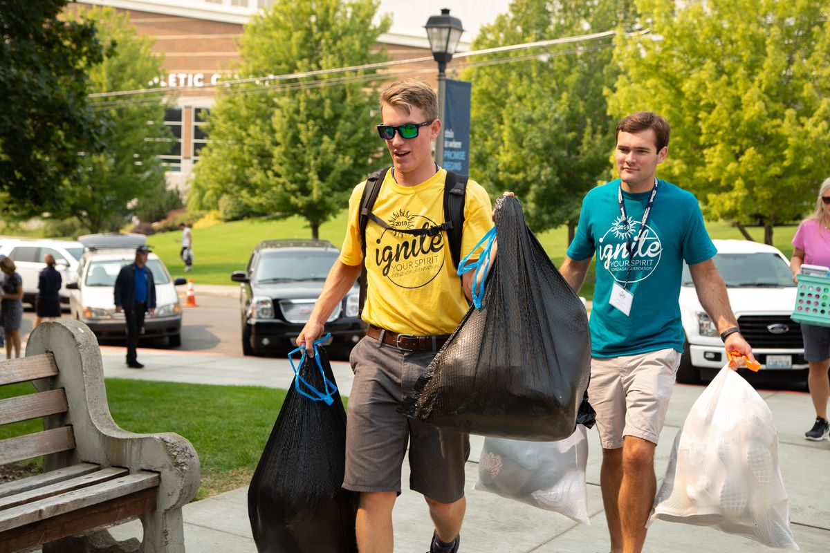Jason Orr, left, and Matthew Morgan carry trash bags filled with the personal belongings of a freshman during Gonzaga Move In day on Aug. 24, 2018. Helpers in yellow are Orientation Super Group leaders, while helpers in teal are Small Group leaders for the weekend's various activities. (Libby Kamrowski / The Spokesman-Review)