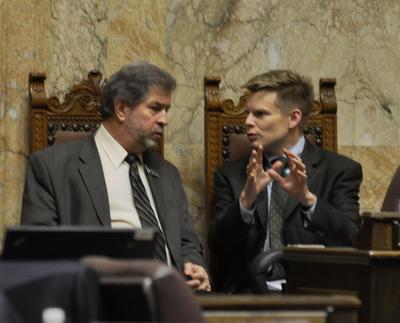 OLYMPIA -- Rep. Jamie Pedersen, D-Seattle, the prime sponsor of the universal background check bill, talks with Rep. Steve Kirby, D-Tacoma, one of its key opponents, before debate starts. (Jim Camden)