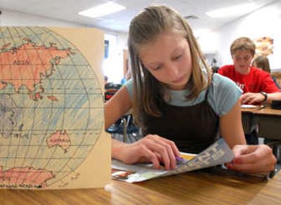 
Sixth-grader Bailey Powell reads from a current events publication for a social studies assignment Wednesday at Canfield Middle School. Teacher Nick Edwards uses the small-supplies stipend to purchase the periodicals and paper goods, like the folder at left, on which students drew world maps. 
 (Jesse Tinsley / The Spokesman-Review)