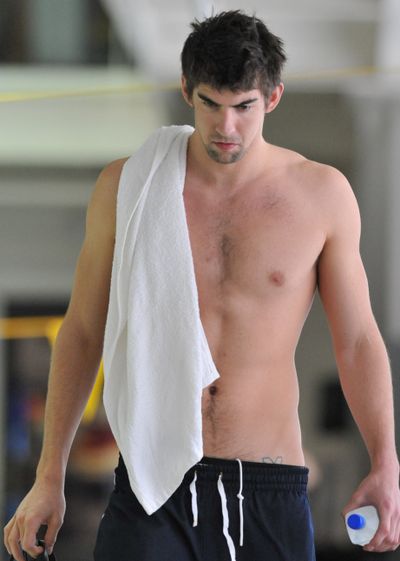 Olympic gold medalist Michael Phelps walks toward reporters to answer questions before training in February. The swimming superstar was suspended for three months and had his training stipend revoked by USA Swimming, after a photo of him smoking marijuana appeared in a British  tabloid. (Associated Press / The Spokesman-Review)