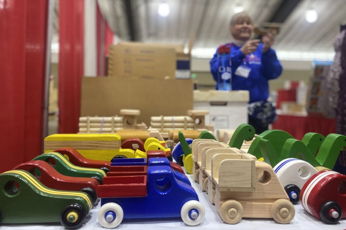 Volunteer Pinki Culbertson unloads wooden trucks from boxes and arranges them on a table at the Christmas Bureau on Tuesday in preparation for opening day.  (Roberta Simonson/The Spokesman-Review)