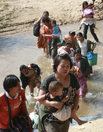 Myanmar citizens cross the Moei river as they flee to Thailand on Monday following fighting between Myanmar soldiers and ethnic Karen fighters.  (Associated Press)