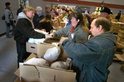 
Longtime volunteers Leo and Michelle Pike hand out turkeys and dinner ingredients at the Salvation Army in Spokane on Tuesday. 
 (Christopher Anderson / The Spokesman-Review)