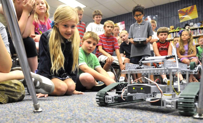 Taylor Smith, left, watches as robot operator Joshua Hall, holding the remote, at right, maneuvers a tracked vehicle through the legs of a chair Wednesday, during a summer school session at Broadway Elementary. Fourth- and fifth-grade students got a chance to operate robots, which they dubbed “Mars rovers” in keeping with the space theme of the session. (Jesse Tinsley)