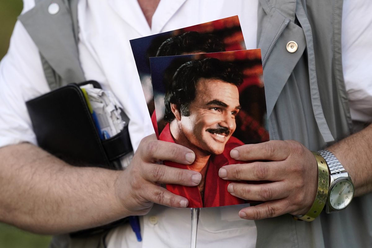 A guest holds programs during the unveiling of a memorial sculpture of the late actor Burt Reynolds at Hollywood Forever Cemetery, Monday, Sept. 20, 2021, in Los Angeles. Reynolds died in 2018 at the age of 82.  (Chris Pizzello)