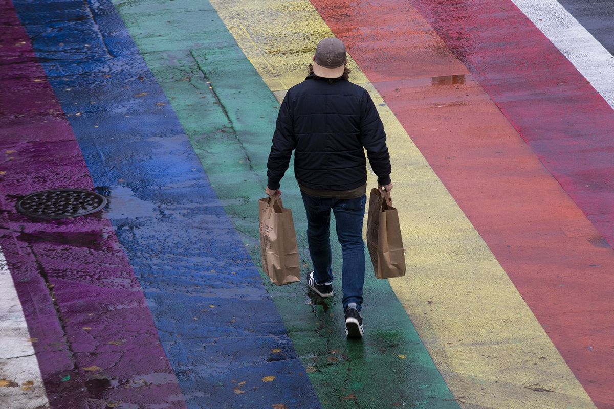 A shopper crosses the street at the intersection of East Pike Street and Broadway in Seattle’s Capitol Hill neighborhood in October 2021.  (Ellen M. Banner/The Seattle Times)