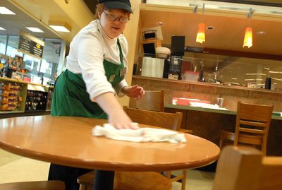 Lisa Heberling, who is visually impaired, cleans tables at the Starbuck’s inside Safeway at Ash Street and Northwest Boulevard in Spokane on Thursday. She is the beneficiary of a push by Safeway and others to hire more disabled workers.   (Jesse Tinsley / The Spokesman-Review)