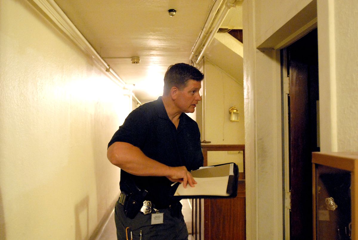 In the hallway of a downtown apartment building, Spokane police Detective Bill Marshall talks with the occupant of an apartment where a registered sex offender is supposed to be living. The offender was not there, and the occupant said he only stayed there occasionally.  (Jesse Tinsley / The Spokesman-Review)