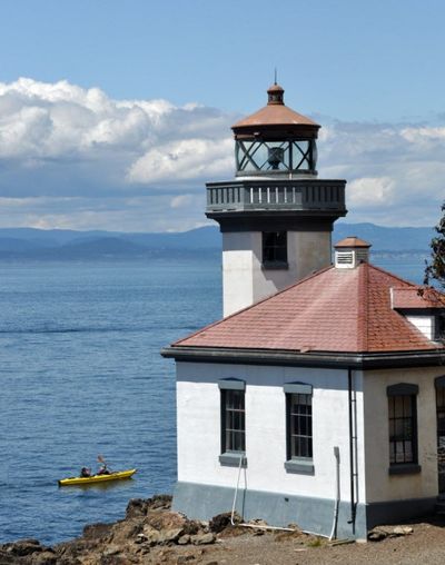 A sea-kayaker paddles by the lighthouse at Lime Kiln Point, a 36-acre Washington State Park on the west side of San Juan Island. The day-use park is a popular destination for island visitors and bicyclists. It's known as a standout land-based facility for viewing whales. (Rich Landers)