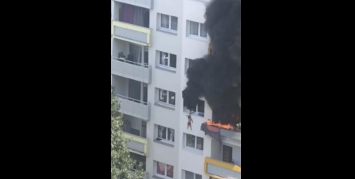 In this grab taken from video, a boy hangs from a window as flames engulfed an apartment as onlookers below prepare to catch him, in Grenoble, France, Tuesday, July 21, 2020. A boy and a toddler escaped a blaze at an apartment in the southeastern French city of Grenoble on Tuesday after they jumped into the arms of residents. The two brothers, aged three and 10 years old, were hanging from a window as flames engulfed their home and onlookers below screamed for them to jump down. (UGC)