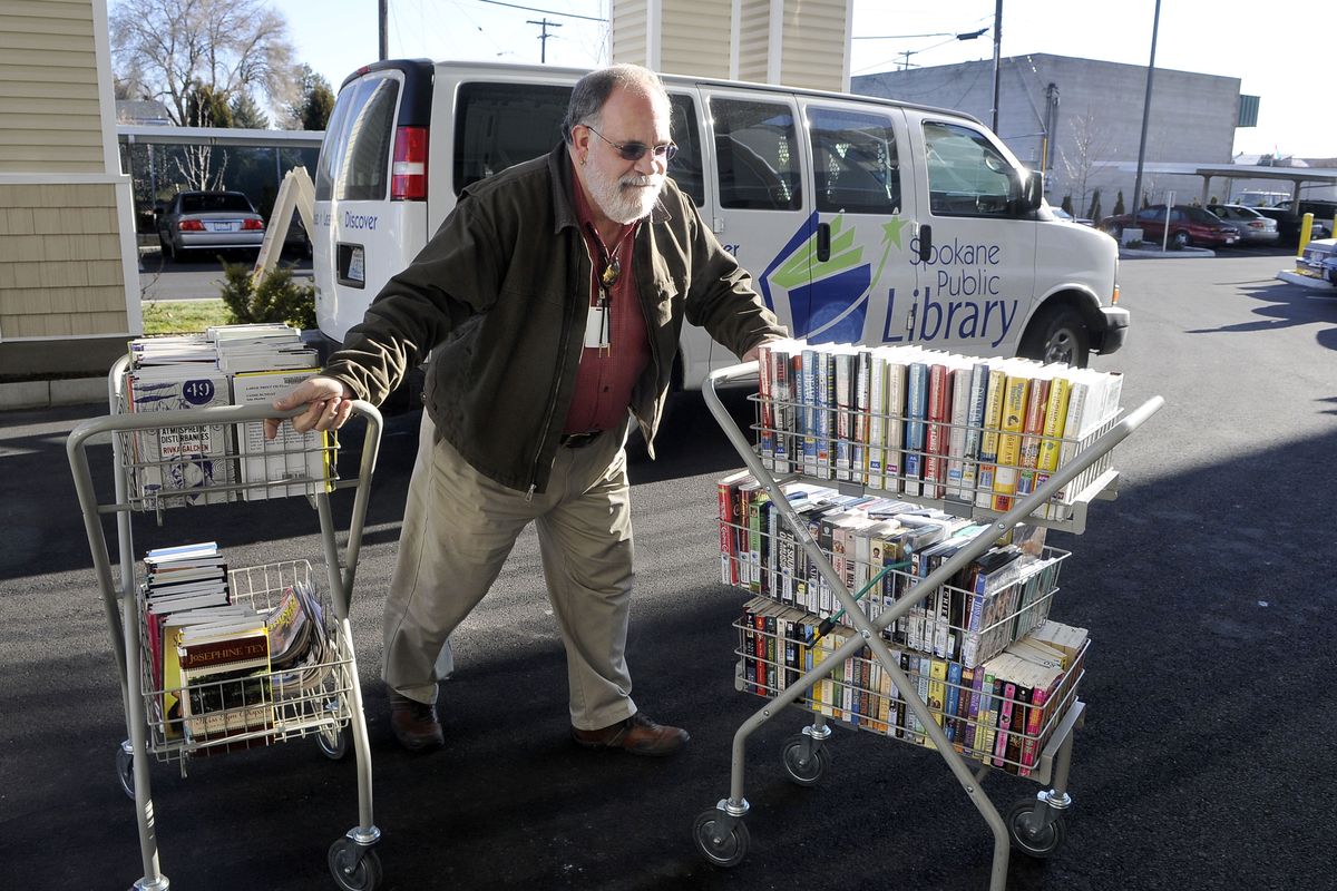 Al Kiefer, of the Spokane Public Library, wheels a load of books and movies into the Vintage, a senior independent living community in Spokane, as part of the library’s Outreach Program, on Dec. 2. (PHOTOS BY DAN PELLE)