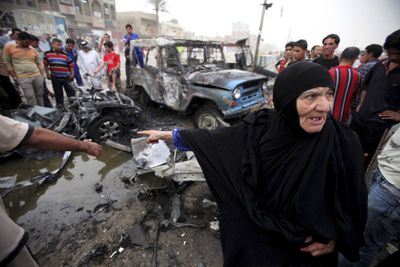 A woman gestures toward the wreckage of a car destroyed in a car bomb explosion in Baghdad’s Shiite enclave of Sadr City, Iraq, Wednesday.  (Associated Press / The Spokesman-Review)