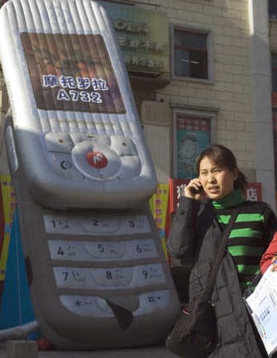 A Chinese woman uses her mobile phone near a balloon shaped like a mobile phone on the streets of Beijing, China. Associated Press
(FILE Associated Press / The Spokesman-Review)