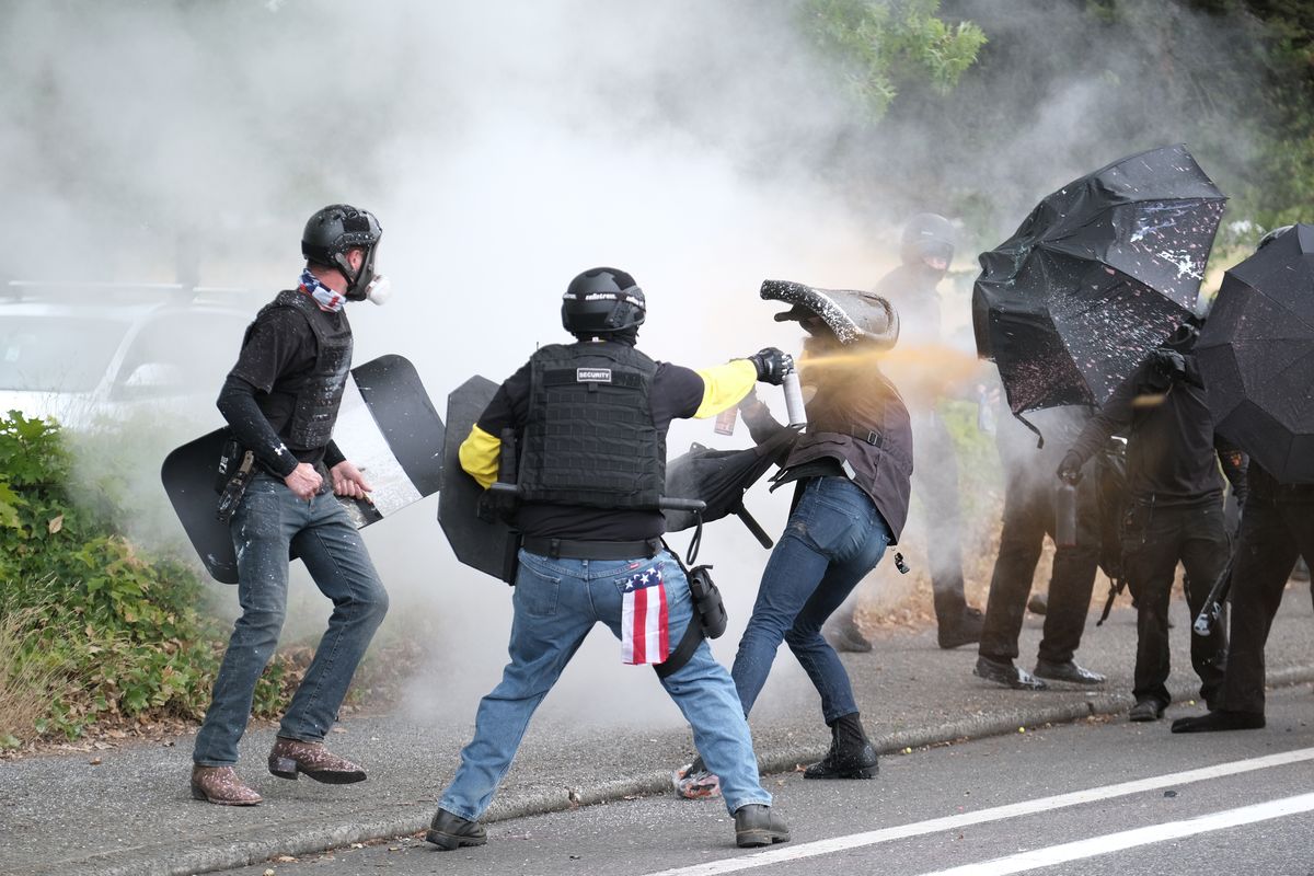 Members of the far-right group Proud Boys and antifascist protesters spray bear mace at each other Aug. 22 during clashes between the politically opposed groups in Portland, Ore. Police in Portland have been criticized that they did little to prevent violent clashes between right- and left-wing protesters on Sunday.  (Alex Milan Tracy)