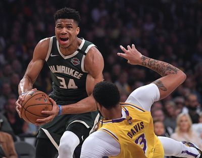 In this March 6, 2020 photo, Milwaukee Bucks forward Giannis Antetokounmpo (34) knocks down Los Angeles Lakers forward Anthony Davis as he drives to the basket during the first half of an NBA basketball game in Los Angeles. Antetokounmpo is spending much of his time during the coronavirus-imposed hiatus working out, helping care for his newborn son and playing occasional video games. What the reigning MVP isn’t doing very often is shooting baskets now that the NBA has closed down team practice facilities. (Mark J. Terrill / Associated Press)