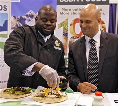 In this July 17, 2012 photo Kern Halls, , a former Disney World restaurant manager who now works in school nutrition Orange County (Fla.) Public Schools, left, demonstrates the making of a wrap for school lunches during the School Nutrition Association conference in Denver asWhite House chef Sam Kass watches. There are plenty of vegetables and other healthy options on school menus these days. The challenge is getting children to eat them.  (Ed Andrieski / AP Photo/)