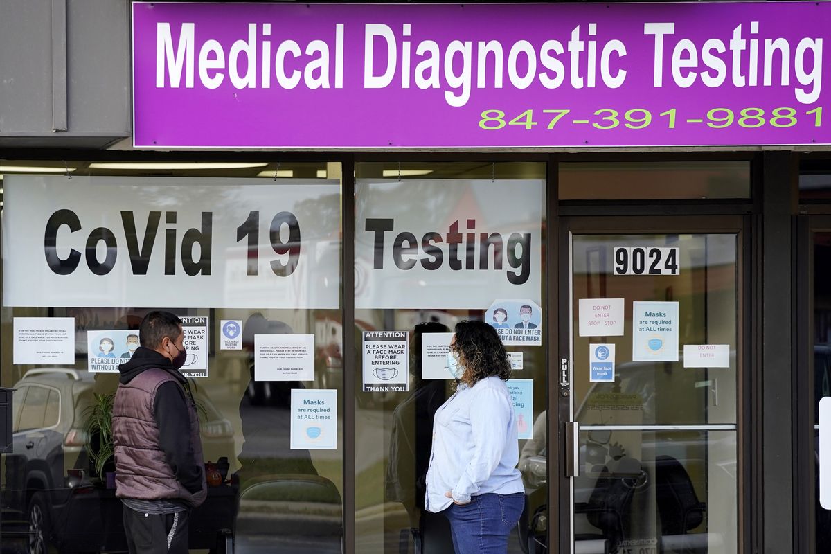 Exam Corp Lab employee, right, wears a mask as she talks with a patient lined up for COVID-19 testing in Niles, Ill., Wednesday, Oct. 21, 2020.  (Nam Y. Huh)