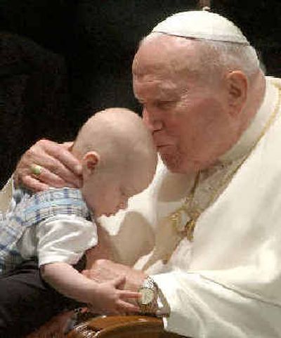 
Pope John Paul II, known for his love of children, kisses a child at the end of his general audience last June. 
 (File/Associated Press / The Spokesman-Review)