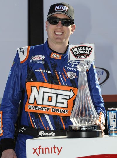 Kyle Busch stands with the trophy in victory lane after winning a NASCAR XFinity Series auto race at Atlanta Motor Speedway Saturday. (John Amis / Associated Press)