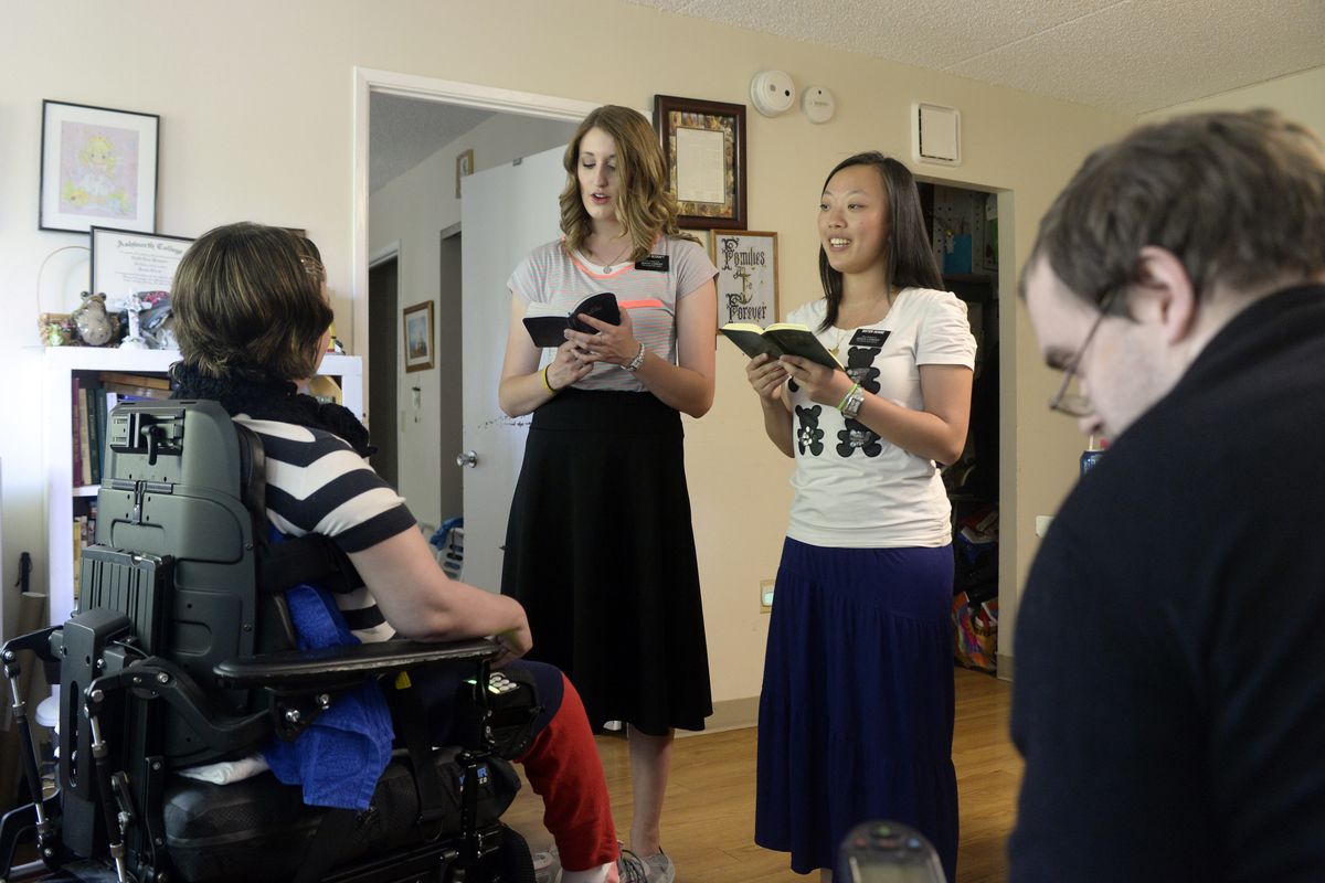 Mormon missionaries Karlee Becraft, center left, and Xueying Huang sing the hymn “Nearer My God to Thee” in both English and Mandarin for Jamie, left, and Michael Clark during a scheduled visit to the couple with physical disabilities on July 29. (Jesse Tinsley)