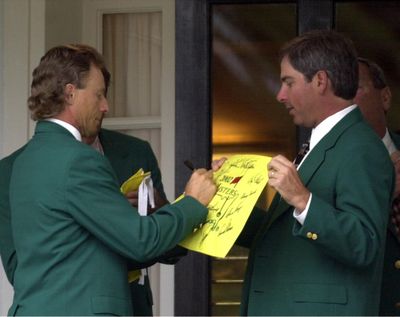 In this Tuesday, April 9, 2002, file photo, former two-time Masters Champion Bernhard Langer, left, signs an autograph for fellow former champion Fred Couples, right, at the Augusta National Golf Club prior to the annual Champions dinner at the 2002 Masters in Augusta, Ga. Even past champions aren’t always sure where to sit at the dinner. (Dave Martin / Associated Press)