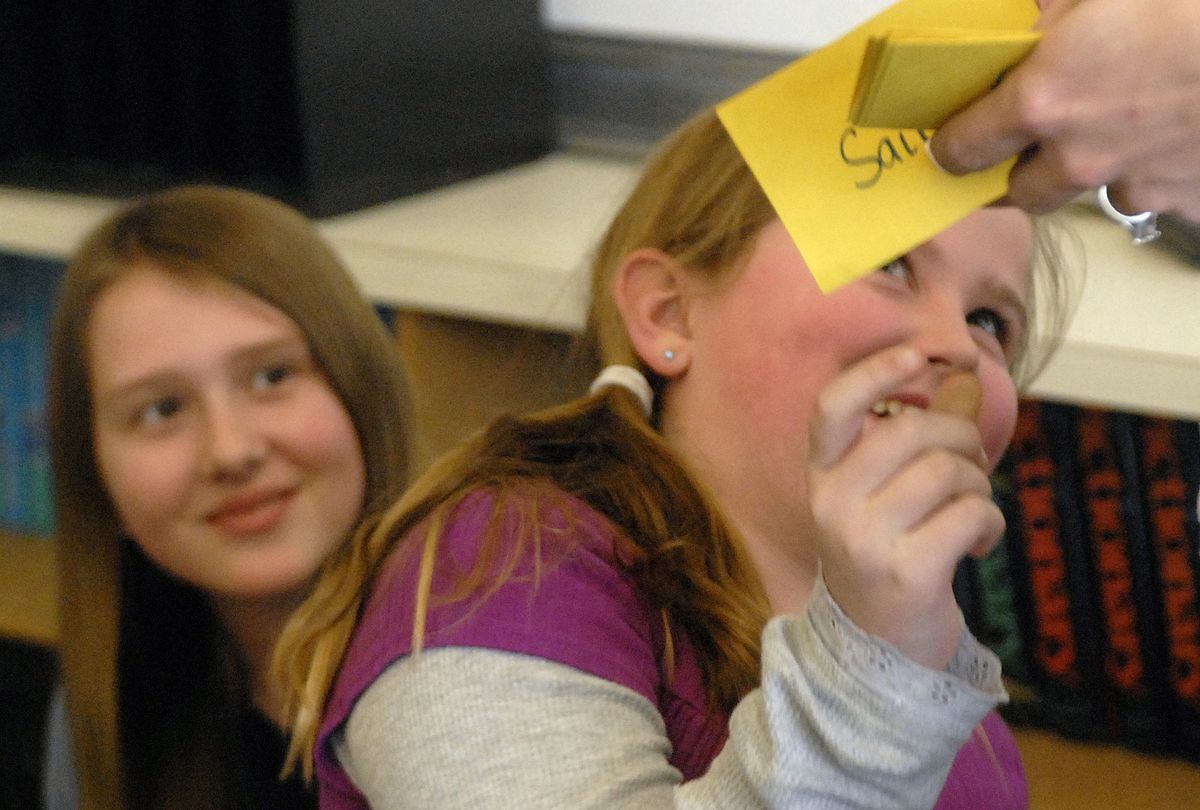 Fourth-grader Savanah Parker returns her fate card to teacher Haley Murray, with fifth-grader Alyssa Gottberg looking on. (J. Rayniak / The Spokesman-Review)