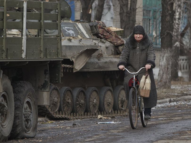 A resident rides a bicycle passing by an armored vehicle in Debaltseve, Ukraine, Friday, Feb. 20, 2015. After weeks of relentless fighting, the embattled Ukrainian rail hub of Debaltseve fell Wednesday to Russia-backed separatists, who hoisted a flag in triumph over the town. The Ukrainian president confirmed that he had ordered troops to pull out and the rebels reported taking hundreds of soldiers captive.  (AP Photo/Vadim Ghirda)