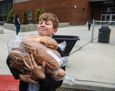 Salk Middle School student, Balien Robinson, 12, is up to his chin in sliced bread as he helps deliver food to the Bite2Go program at the school, Wednesday, April 1, 2020. Balien, along with his sister, Aurelia and father, Michael, contributed many items for the event. (Dan Pelle / The Spokesman-Review)