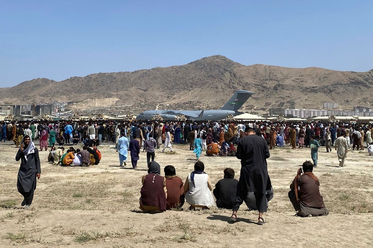 FILE - Hundreds of people gather near a U.S. Air Force C-17 transport plane at a perimeter at the international airport in Kabul, Afghanistan, on Aug. 16, 2021. A whistleblower has alleged that Britain’s Foreign Office abandoned many of the nation’s allies in Afghanistan and left them to the mercy of the Taliban during the fall of the capital, Kabul, because of a dysfunctional and arbitrary evacuation effort.  (Shekib Rahmani)