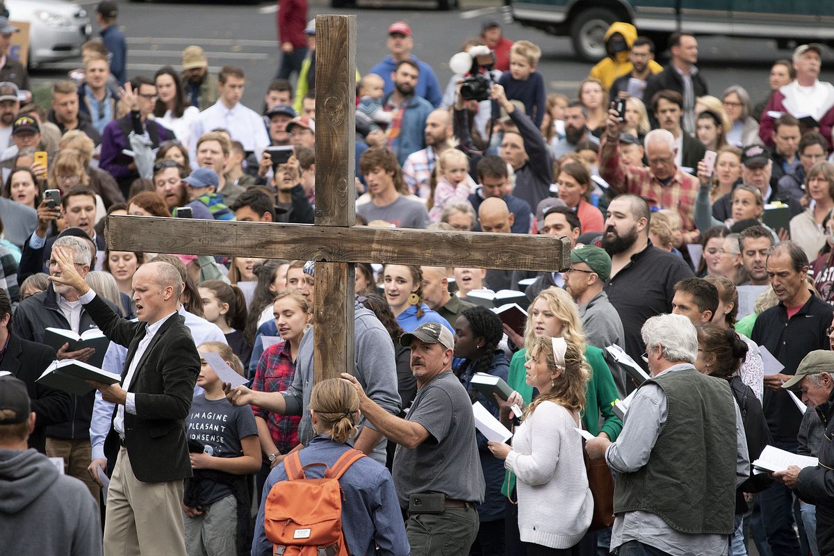 Members of Christ Church sing a hymn over the noise from counter-protesters playing drums during “psalm sing” on Friday, Sept. 25, 2020, outside city hall in Moscow, Idaho. Church members were protesting against a city public-health order that requires people to either socially distance or wear a face mask in public. (Geoff Crimmins/The Moscow-Pullman Daily News via AP) ORG XMIT: IDMOS101  (Geoff Crimmins/The Moscow-Pullman Daily News )