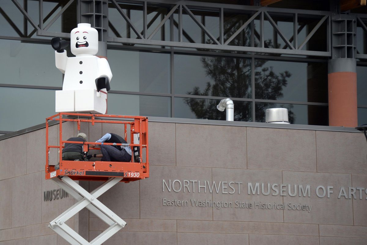 John Richardson and Tammy Gabbert of the Northwest Museum of Arts and Culture fasten a seven-foot replica of a LEGO toy character on the roof of the museum, Wednesday, Nov. 4, 2015. The figure, one of three cut from foam, is displayed to promote a new LEGO art exhibit which opens Nov. 14, 2015. (Jesse Tinsley / The Spokesman-Review)