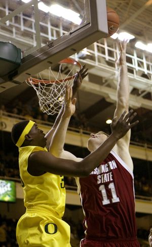 Washington State center Aron Baynes, right, takes it to the hoop against Oregon center Michael Dunigan during the first half of their NCAA basketball game in Eugene on Saturday, Jan. 17, 2009. (Associated Press)