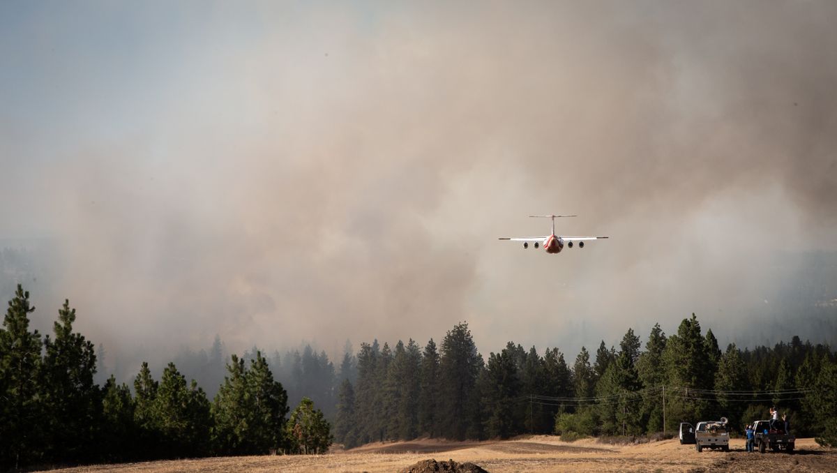 A firefighting aircraft flies low into the blaze of the Andrus Road Fire on Monday in Cheney.  (Libby Kamrowski/ THE SPOKESMAN-REVIEW)