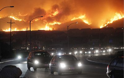 Residents flee their hillside homes Monday during a  wildfire in Los Angeles.  (Associated Press / The Spokesman-Review)