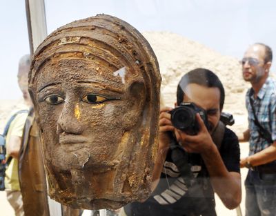 A photographer shoots a gilded silver mummy mask found on the face of the mummy of the second priest of Mut, as it is displayed during a news conference in front of the step pyramid of Saqqara, in Giza, Saturday, July 14, 2018. Archaeologists say they have discovered a mummification workshop dating back some 2,500 years at an ancient necropolis near Egypt’s famed pyramids. (Amr Nabil / Associated Press)