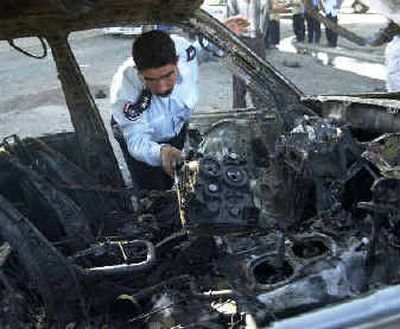 
An Iraqi policeman inspects damage done to the car of Lt. Col. Alaa al-Din Arif, who was killed after a car bomb exploded nearby, in Baghdad on Sunday. A car bomb detonated early Sunday in a western Baghdad neighborhood, killing two police officers on patrol, the Interior Ministry said. 
 (Associated Press / The Spokesman-Review)