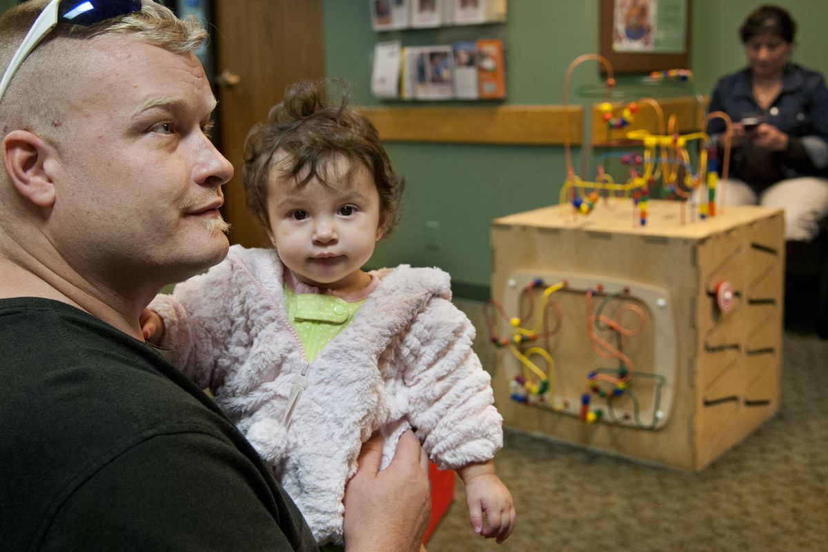 Blake Wiens, his daughter, McKaella, 11 months, and fiancee, Rosa Chavira, right, visit the Women, Infants and Children nutrition program office in the Spokane Regional Health District building Tuesday. “I’m Nosey Rosey,” Chavira said. “We just had to see if WIC was still open.” The federal government shutdown leaves WIC with only nine days’ worth of funding. (Dan Pelle)