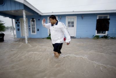 George Soberanis puts his hand up to block the pelting rain from Hurricane Dolly as he wades through floodwaters outside his house Wednesday in Los Fresnos, Texas.  (Associated Press / The Spokesman-Review)