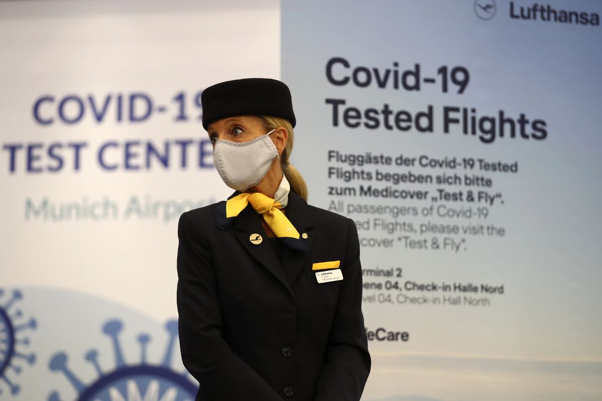 A flight attendant stands in front of the entrance of a new Lufthansa corona quick test center at the airport in Munich, Germany, Thursday, Nov. 12, 2020. Lufthansa starts the first test runs for comprehensive Covid-19 antigen rapid tests on selected routes between Munich and Hamburg.  (Matthias Schrader)