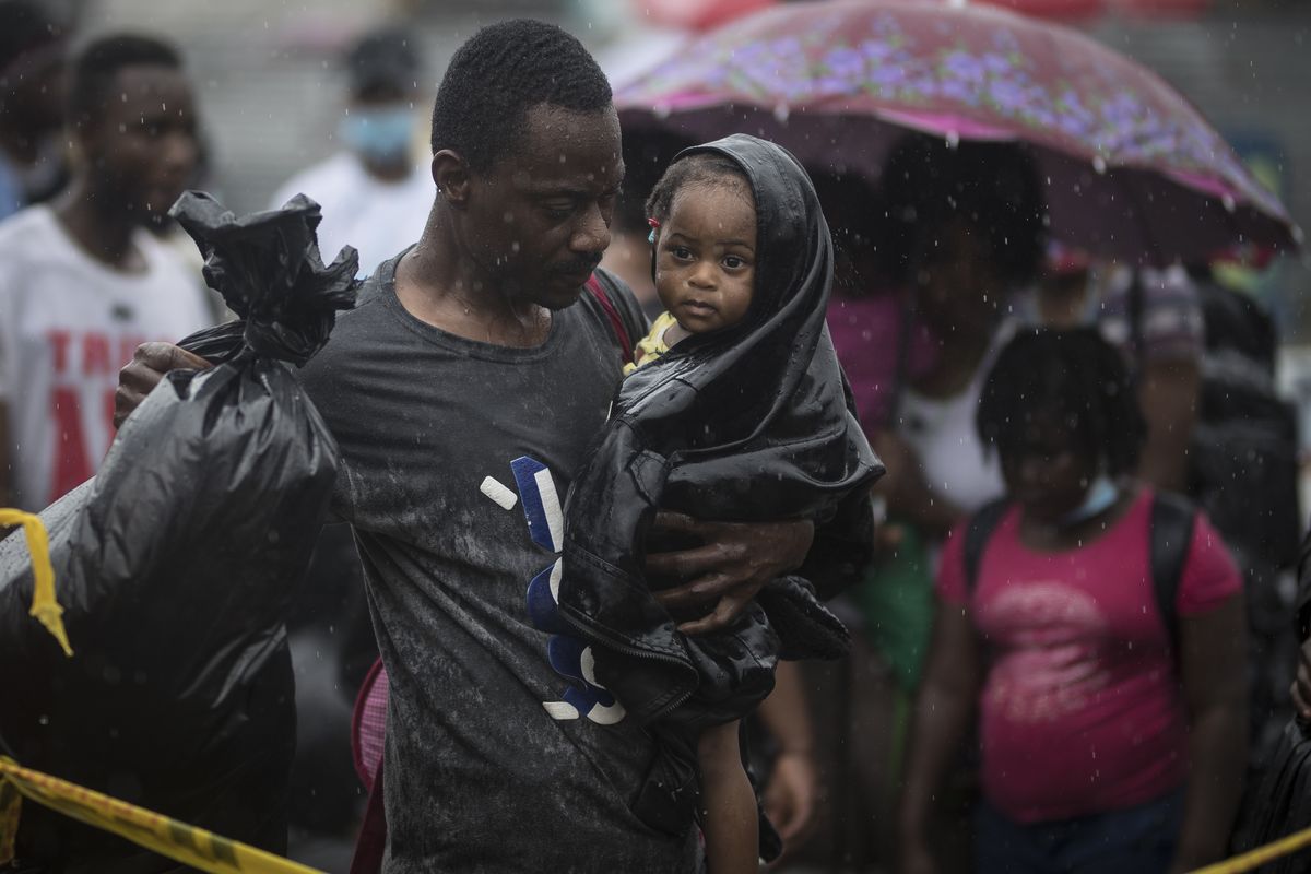 A Haitian migrant carries a baby to a boat that will take them to Capurgana, on the border with Panama, from Necocli, Colombia, early Thursday, July 29, 2021. Migrants have been gathering in Necocli as they move north towards Panama on their way to the U.S. border.  (Ivan Valencia)