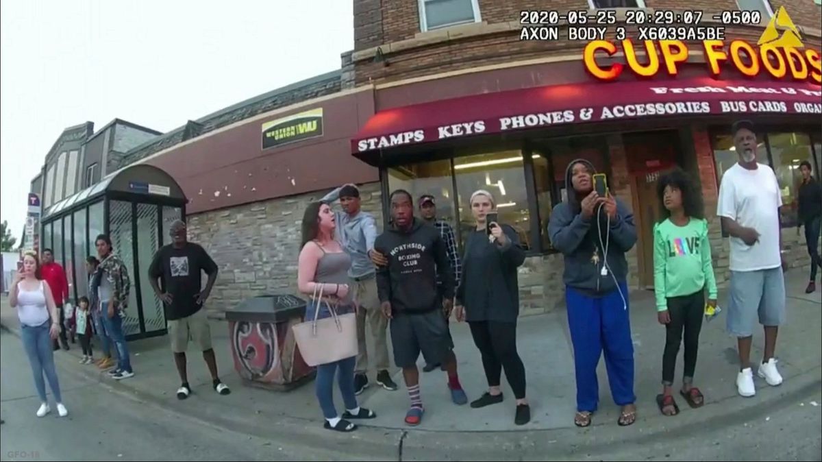 In this image from a police body camera, bystanders including Alyssa Funari, left filming, Charles McMillan, center left in light colored shorts, Christopher Martin center in gray, Donald Williams, center in black, Genevieve Hansen, fourth from right filming, Darnella Frazier, third from right filming, witness as then Minneapolis police officer Derek Chauvin on May 25, 2020, pressed his knee on George Floyd’s neck for several minutes, killing Floyd. (HOGP)