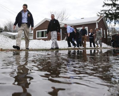 New York Gov. Andrew Cuomo walks along a watery driveway while surveying the aftermath of last week’s lake-effect snowstorms on Monday in West Seneca, N.Y. (Associated Press)