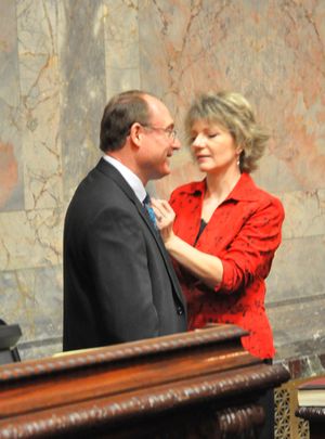 Diane Baxter adjusts a flag pin on her husband's lapel before Jeff Baxter is sworn in to a seat in the state Senate. (Jim Camden/The Spokesman-Review)