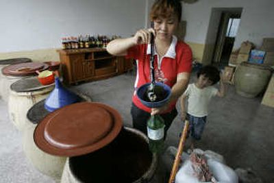 
A Chinese woman fills up a plastic bottle with soy sauce in June at a family shop in Xiamen, China. The world's most populous country is awash in such tiny operations. Associated Press
 (Associated Press / The Spokesman-Review)