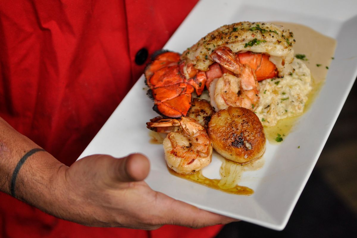 Scratch and Rain chef and new owner Sil Hernandez shows of the Ultimate Seafood Trio with lobster tail, scallops and prawns in a lemon cream sauce with Parmesan risotto. (Adriana Janovich / The Spokesman-Review)