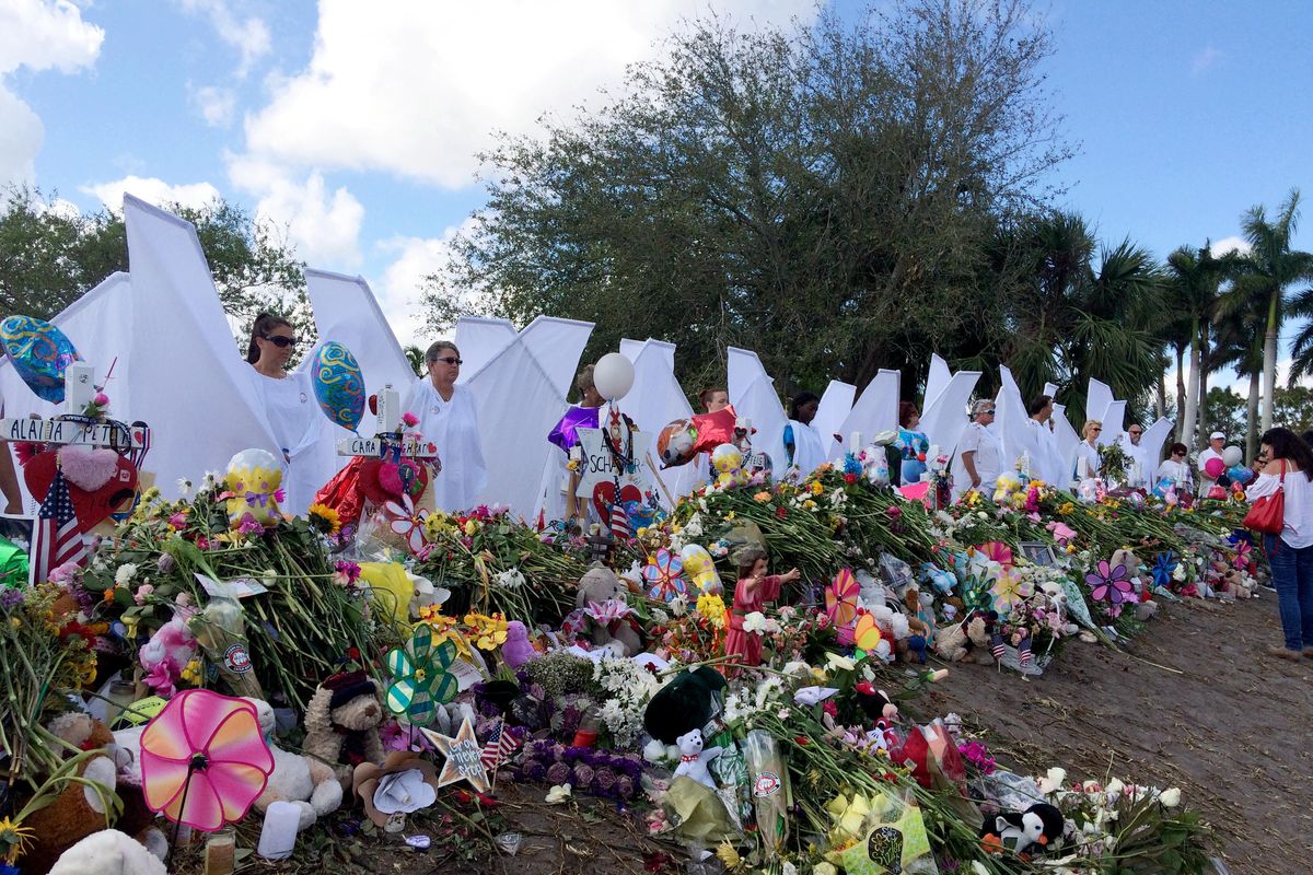 Seventeen people dressed as angels stand Sunday, Feb. 25, 2018, at the memorial outside Marjory Stoneman Douglas High School in Parkland, Fla., for those killed in a shooting on Feb. 14. (Terry Spencer / Associated Press)