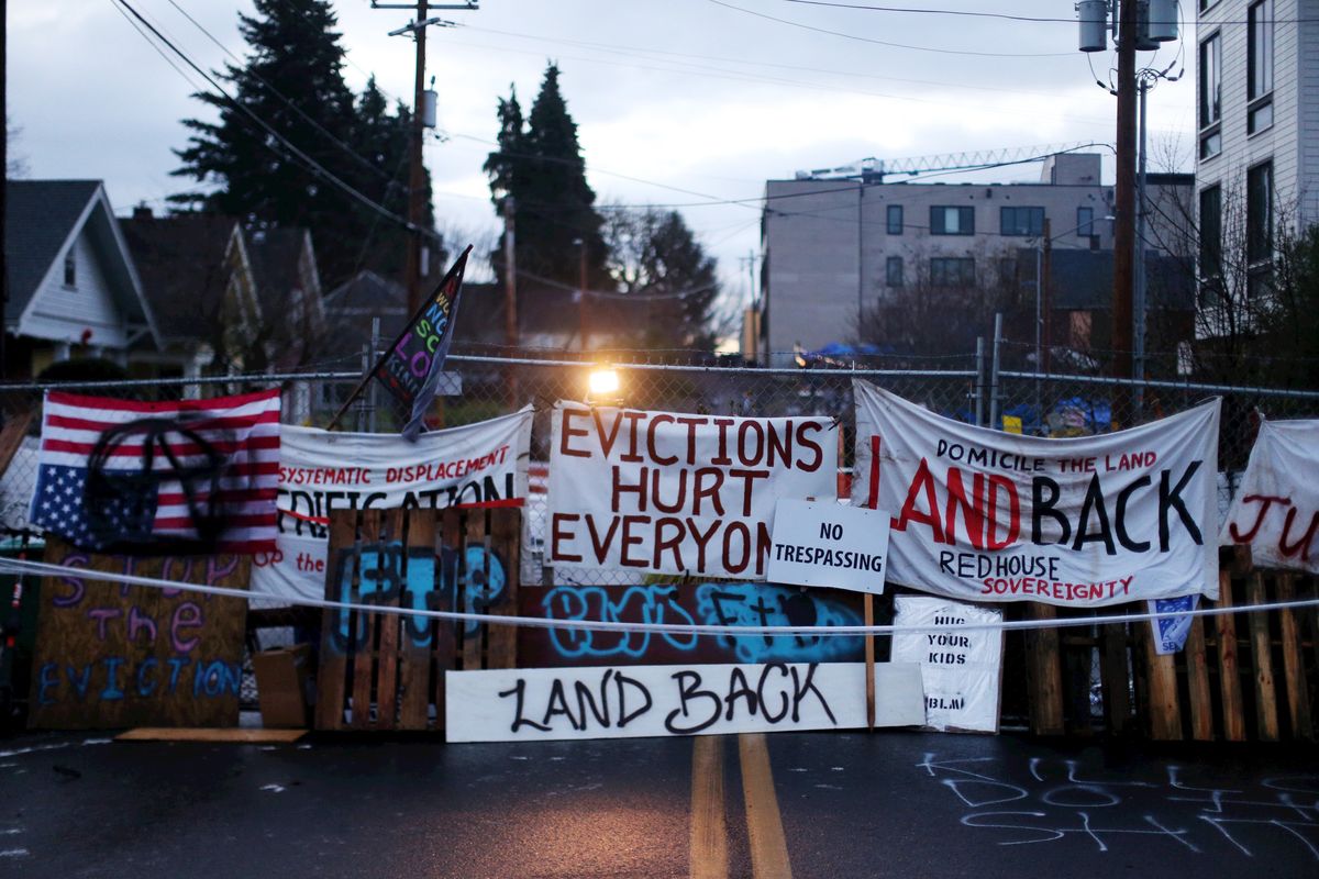Signs and barricades remain outside a house on North Mississippi Avenue in Portland on Wednesday. Makeshift barricades erected by protesters are still up in Oregon’s largest city, a day after Portland police arrested about a dozen people in a clash over gentrification and the eviction of a family from a home.  (Beth Nakamura)