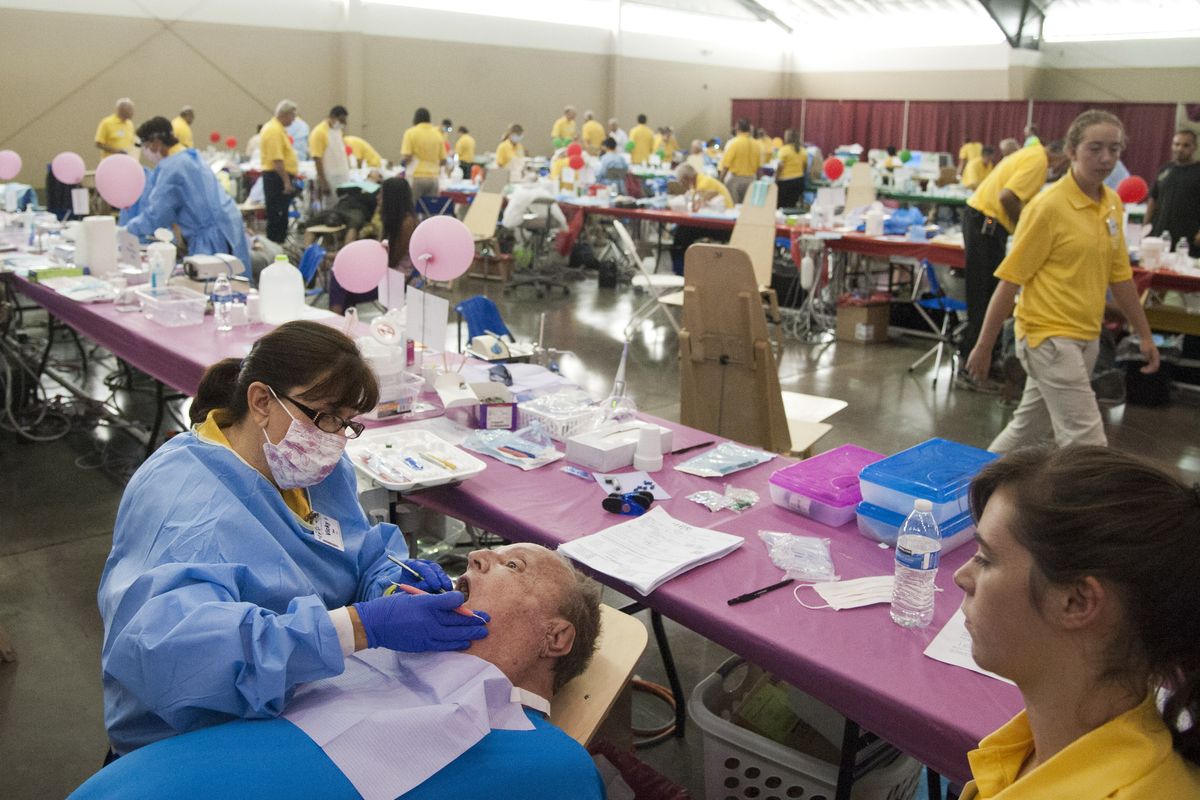 Volunteer dental hygienist Vicki Dye, left, of Sandpoint, Idaho begins a cleaning on patient Ralph White in the dental care area Monday, Aug. 8, 2015 at the Spokane Fair and Expo Center, the site of the Your Best Pathway to Health clinic coordinated by the Seventh Day Adventist church and involving many donors, sponsors and volunteers. All services were delivered free of charge and no questions were asked. At right is volunteer assistant Natalie Harder, 17. (Jesse Tinsley / The Spokesman-Review)