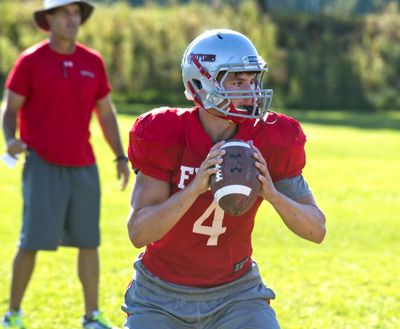 Cole Karstetter takes a few snaps at quarterback under the watch of coach Jim Sharkey during a recent Ferris football practice. (Dan Pelle)