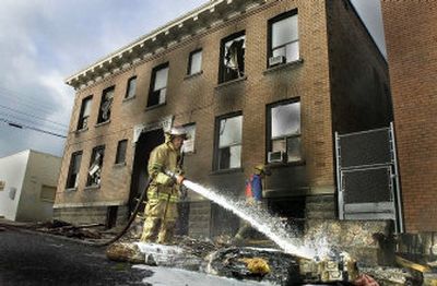 
Spokane firefighters douse smoldering debris pulled from the State Street Flats on Thursday. 
 (The Spokesman-Review)